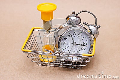 An hourglass and a metal alarm clock in the shopping basket. concept of time Stock Photo