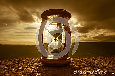 Hourglass Passing of Time Lapse Clouds. An hourglass in front of a bright blue sky with puffy white clouds passing. Time concept. Stock Photo