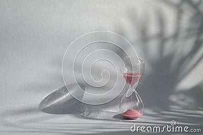 Hourglass sand timer with palm shadow on wall Stock Photo