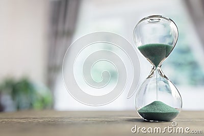 Hourglass time passing in room by window Stock Photo