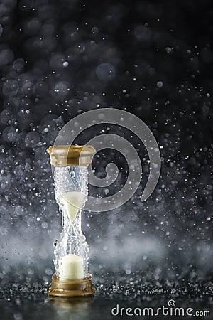 Hourglass under the water drops isolated on black background. Time limited. Deadline. Marketing strategy. Stock Photo