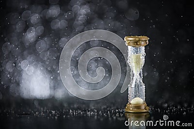 Hourglass under the water drops isolated on black background. Time limited. Deadline. Marketing strategy. Stock Photo