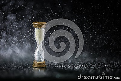 Hourglass under the water drops isolated on black background. Time limited. Deadline. Marketing strategy. Stock Photo