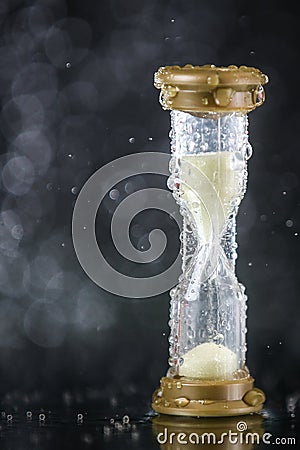 Hourglass under the water drops isolated on black background. Time limited. Deadline. Marketing strategy. Stock Photo