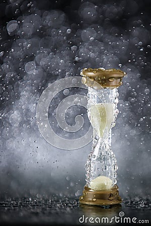 Hourglass under the water drops isolated on black background. Time limited. Deadline. Marketing strategy. Stock Photo