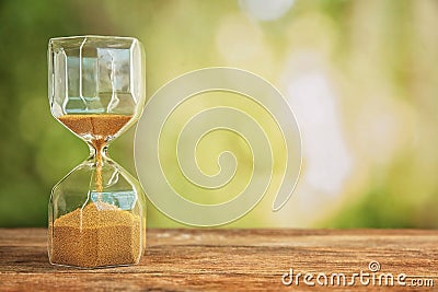 Hourglass on wooden table outdoors. Time management concept Stock Photo