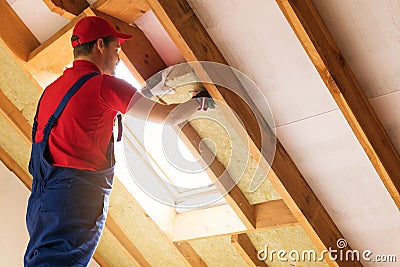 House attic insulation - construction worker installing wool Stock Photo