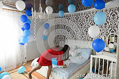 HOUSE AFTER BIRTH. decorated room for a young mother. surprise at home. Mother holds her baby in her arms in a white bedroom. Love Stock Photo