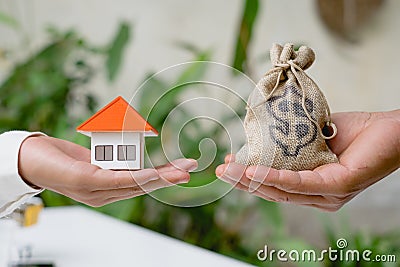 House and coins in the hands of investors.Orange roof house.Save money for buying a new home and borrowing money to plan the real Stock Photo