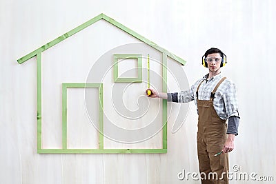 House construction renovation concept handyman carpenter worker man with meter measure and show the model of wooden green house Stock Photo
