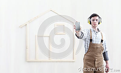 House construction renovation concept handyman carpenter worker man show the mobile phone isolated with the model of a wooden Stock Photo