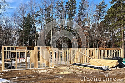 House construction site with wall studs and stacks of wood lumber Stock Photo