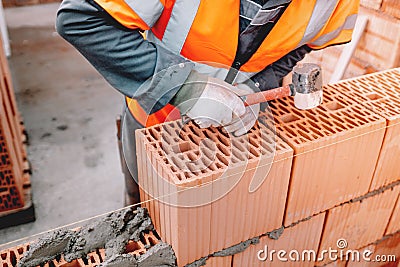 House construction site, worker building the brick wall with trowel, cement and mortar. Stock Photo