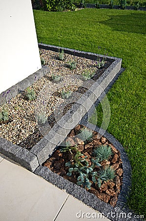 House corner design idea: stone framing as flowerbed, evergreens and lavender plants, terrace Stock Photo