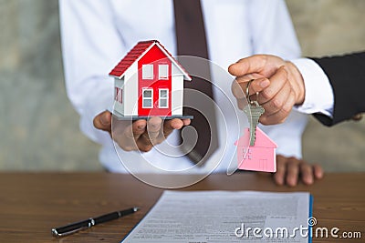 The house dealer holds the red roof house and holds the key to the concept. The customer who buys the product or signs a contract Stock Photo