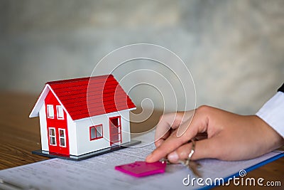 The house dealer holds the red roof house and holds the key to the concept. The customer who buys the product or signs a contract Stock Photo