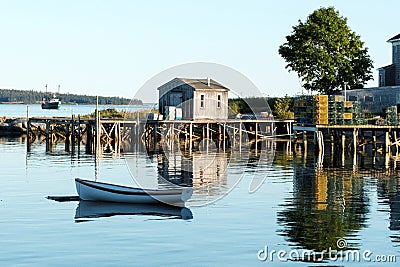 House, dock, row boat and lobster traps reflecting in the water Editorial Stock Photo