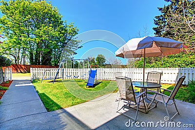 House exterior. Small fenced back yard with patio area and kids playground Stock Photo