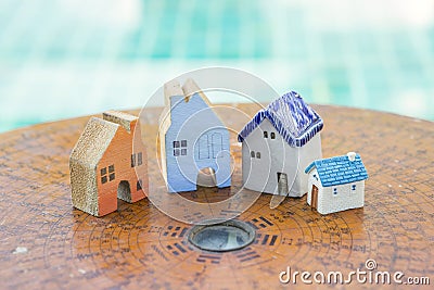 Beautiful miniature house on ancient wooden feng shui compass over blurred blue water background Stock Photo