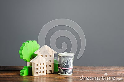 House figurines and a bundle roll dollars. Residential building maintaining cost, utility bills. Modernization housing, improving Stock Photo