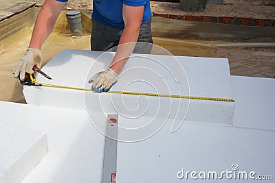 House floor layers construction with waterproofing membrane, styrofoam insulation boards. Worker measuring foam insulation board Stock Photo