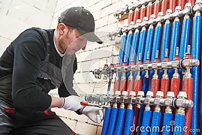 Plumber work. Installing collector for warm water underfloor heating system Stock Photo