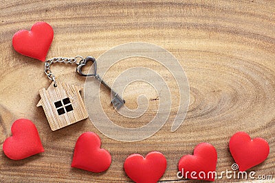 House key in heart shape with home keyring on wood background decorated with mini hearts Stock Photo