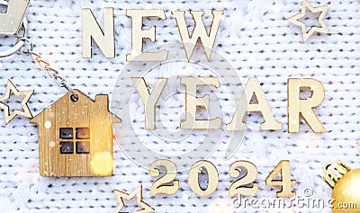 House key with keychain cottage on cozy festive knitted background with stars, bokeh. Happy New Year 2024 wooden letters, greeting Stock Photo