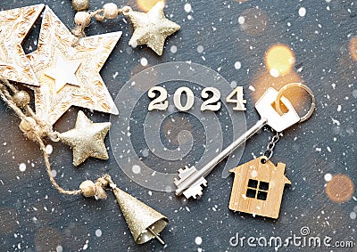 House key with keychain cottage on festive background with stars, lights of garlands. New Year 2024 wooden letters, greeting card Stock Photo