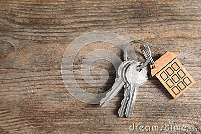 House keys with trinket on wooden background, top view. Stock Photo