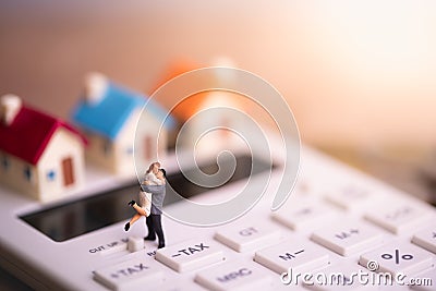 House model and small couple figures in love standing on calculator. Stock Photo