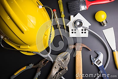 House model with stethoscope and construction tools on black background with copy space.Real estate concept, Repair maintenance c Stock Photo