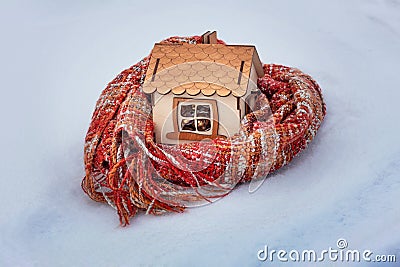 House model wrapped in a warm scarf on white snow in winter, gas and electricity prices. Concept of heating season. European energ Stock Photo