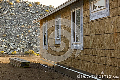 House nearing completion of construction. Stack of boards in the dirt ready for building Stock Photo