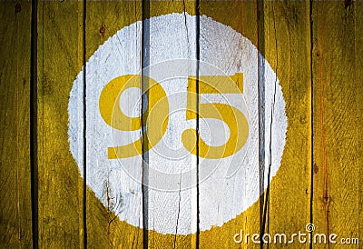 House number or calendar date in white circle on yellow toned wooden door background. Number ninety five 95 Stock Photo