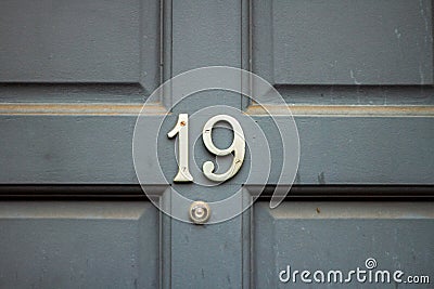 House number 19 with the nineteen in silver on a gray wooden door Stock Photo