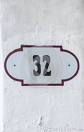 House number 32 thirty two. Black lettering on a white metal plate with brown edge Stock Photo