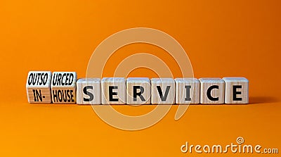 In-house or outsourced service symbol. Turned wooden cubes and changed words In-house service to Outsourced service. Orange Stock Photo