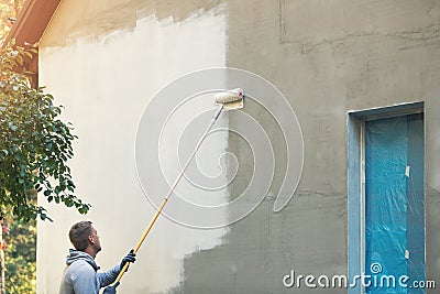 House painter painting building exterior with roller Stock Photo