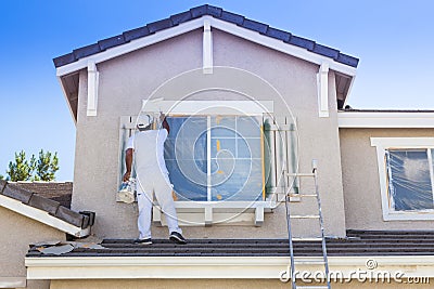 House Painter Painting the Trim And Shutters of Home Stock Photo