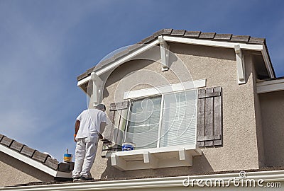 House Painter Painting the Trim And Shutters of Home Stock Photo