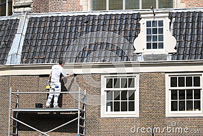 House painter paints a house. Facade with brick wall and white w Editorial Stock Photo