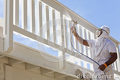 House Painter Spray Painting A Deck of A Home Stock Photo