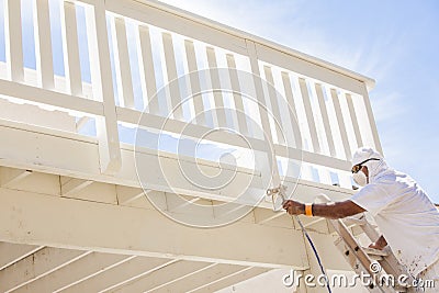 House Painter Spray Painting A Deck of A Home Stock Photo