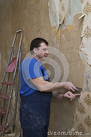 House reconstruction. Worker removes old wallpaper Stock Photo