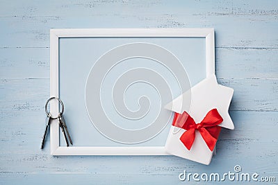 House with ribbon, frame and keychain on wooden background. Buying a new home, planning housewarming, gift or sale of real estate Stock Photo