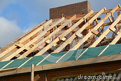 House rooftop wooden frame construction. Incomplete house rooftop roofing construction trusses, vapor barrier, wooden beams, Stock Photo