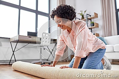 young woman unfolding carpet at home Stock Photo