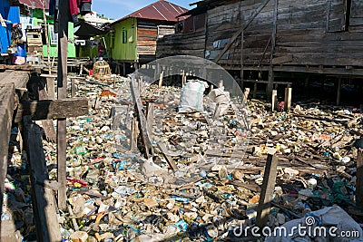 Plastic trash on residential area between houses in asia with a person walking on a wooden way to their home Editorial Stock Photo