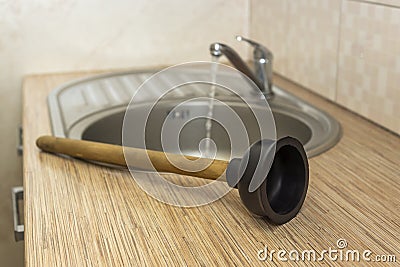 Household plumbing tool for clearing blockages is a plunger at the kitchen sink Stock Photo